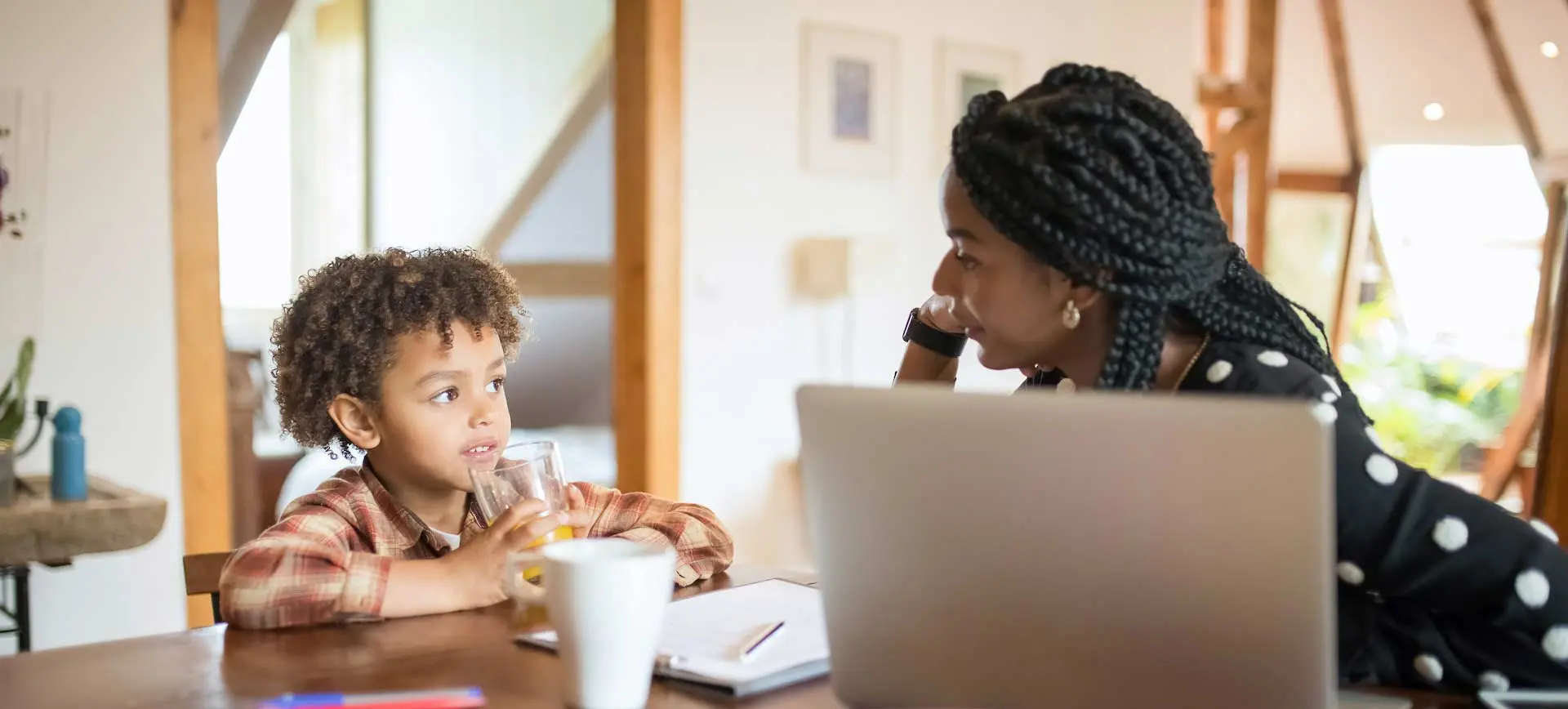 Mother and son having breakfast together at a table with a laptop