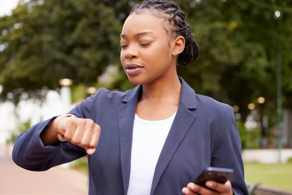 Woman checking the time while looking at her phone after applying for an emergency loan online