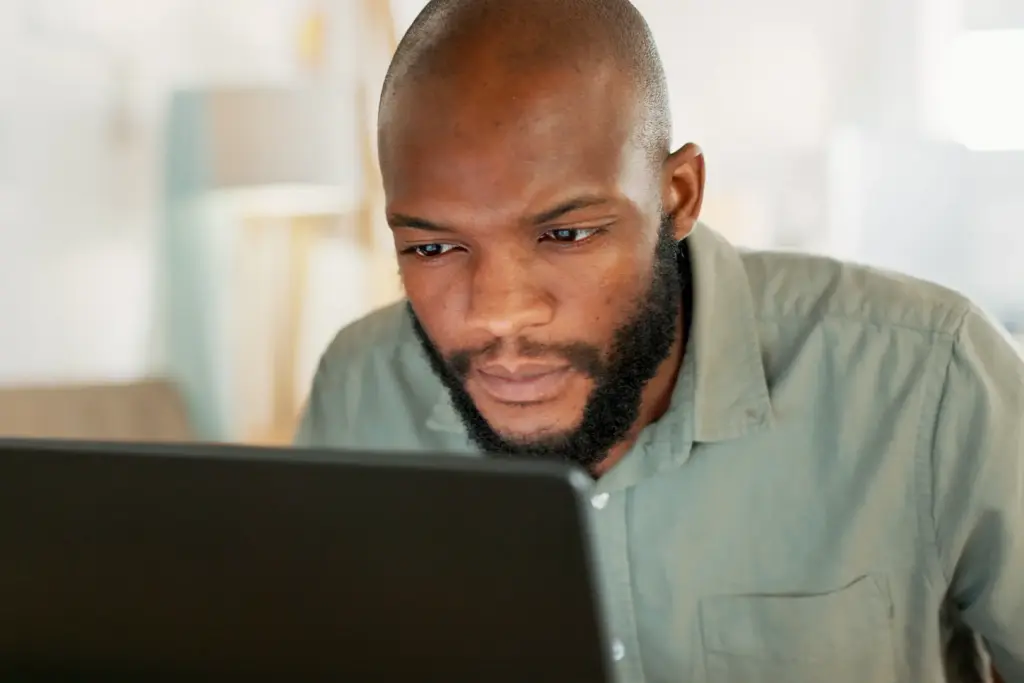 Focused man reviewing his personal information on a laptop after applying for a payday loan