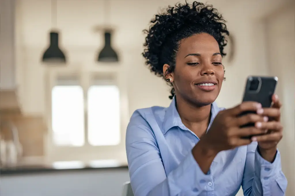 Smiling woman looking at her phone after getting approved for a payday loan in Ohio