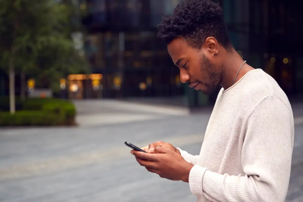 Smiling man using his phone to apply for a payday loan online.