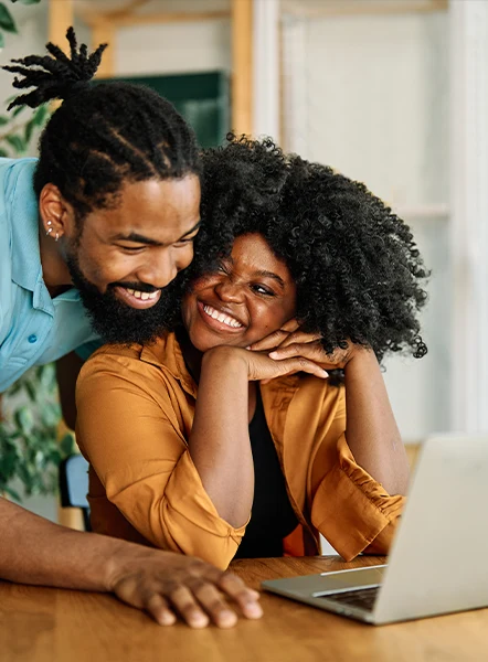 Happy couple reviewing their online payday loan approval on a laptop