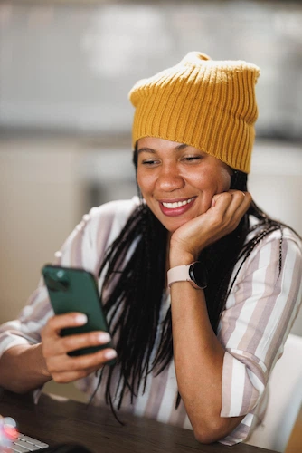 Smiling woman with long braids looking at her smartphone to apply for Maine payday loans