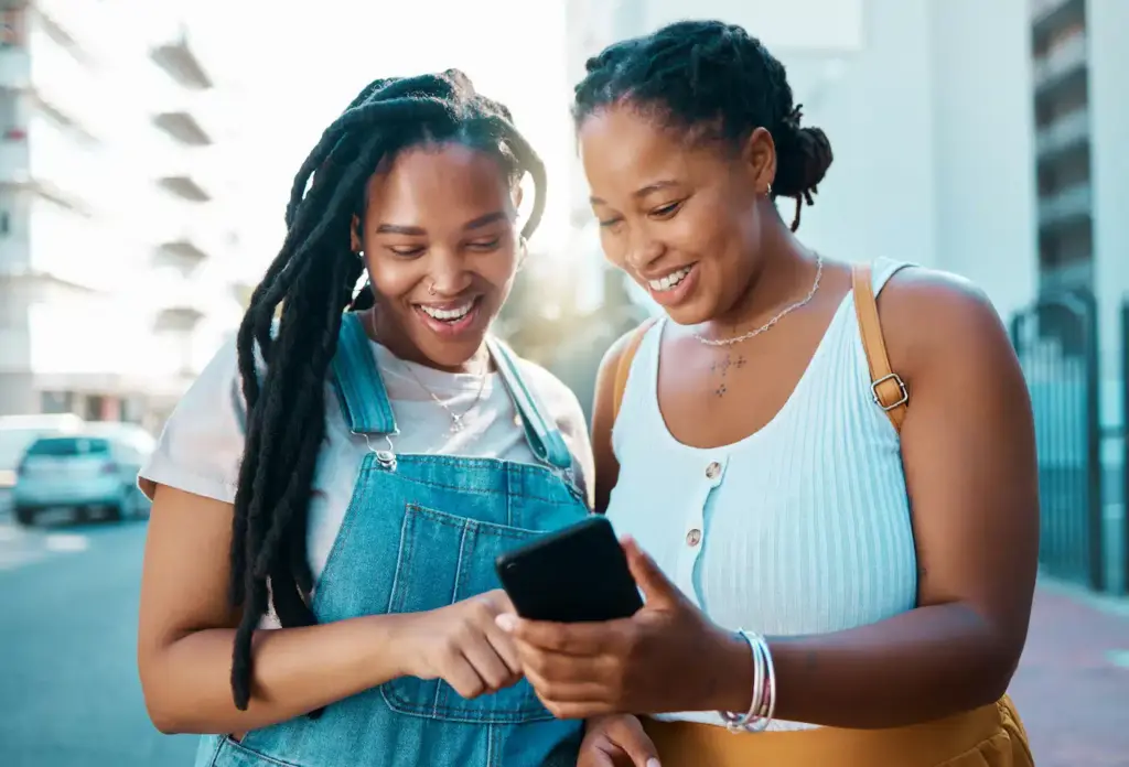 Young women using a smartphone to find quick California-based payday loans while out in the city