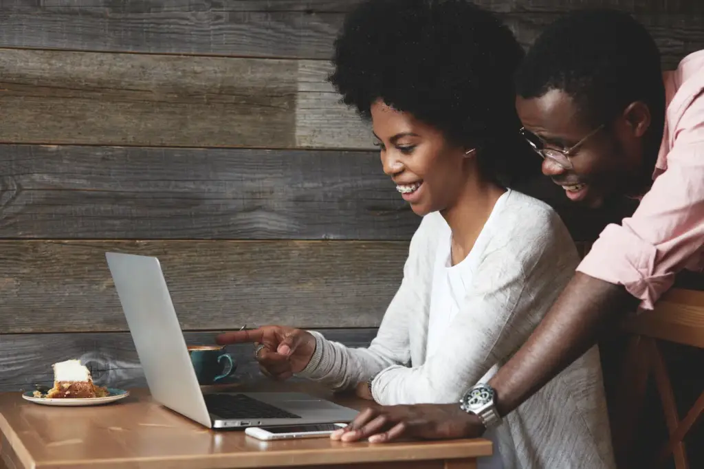 A smiling young woman in a cafe shows her partner how to apply for payday loans in Maryland using her laptop